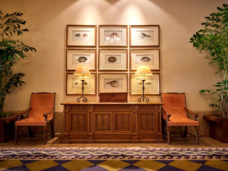 Elegante lobby del Hotel Nikko Alivila con muebles de madera, sillones y cuadros decorativos de peces en la pared