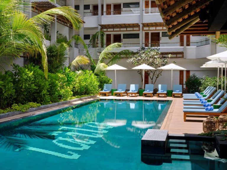 Piscina exterior con tumbonas y sombrillas del resort Laïla Seychelles, rodeada de vegetación tropical