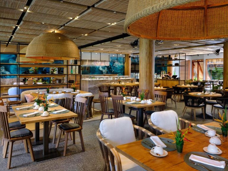 Restaurante interior con decoración tropical y mesas de madera en Laïla Seychelles Tribute Portfolio Resort