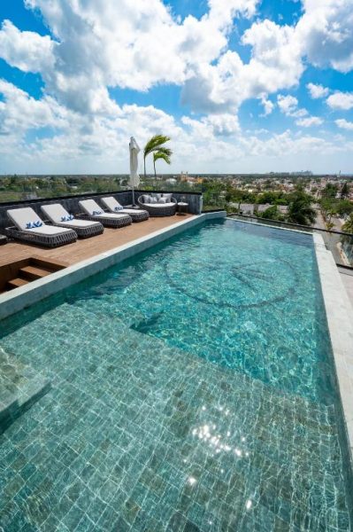 Piscina infinita en la azotea del ApartHotel Kippal Modern Oasis con tumbonas y vistas panorámicas de la ciudad
