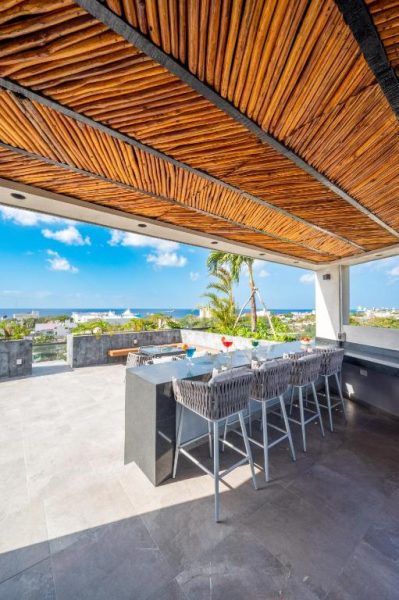 Terraza bar con techo de bambú y vistas al mar en Kippal Modern Oasis ApartHotel