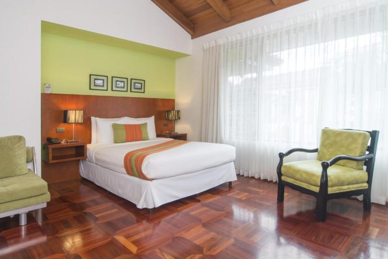 Habitación doble con suelos de madera y decoración en verde del Terrazas de Golf Boutique Hotel