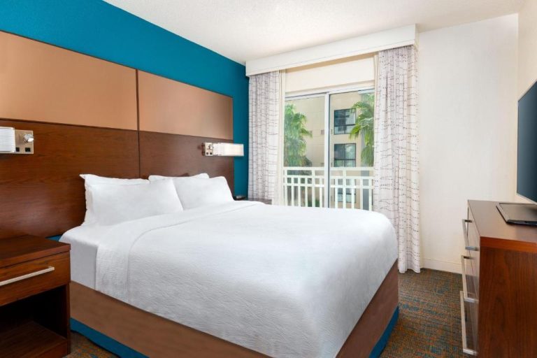 Habitación con cama king size y balcón del Residence Inn Tampa Downtown con vistas a palmeras