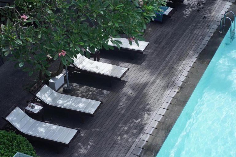 Tumbonas junto a la piscina exterior con tarima de madera en The Vira Bali Boutique Hotel & Suite