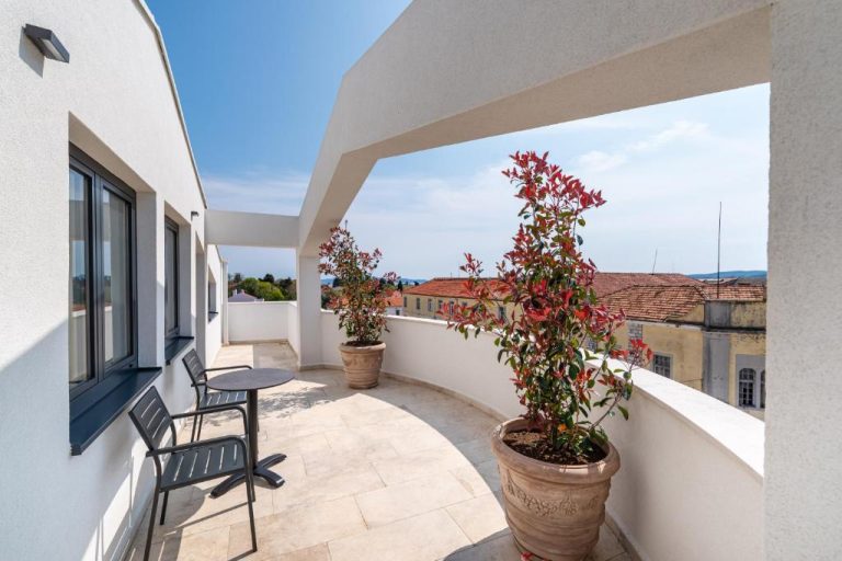 Terraza exterior con sillas y plantas del Miramare Hotel con vistas panorámicas a los tejados de la ciudad