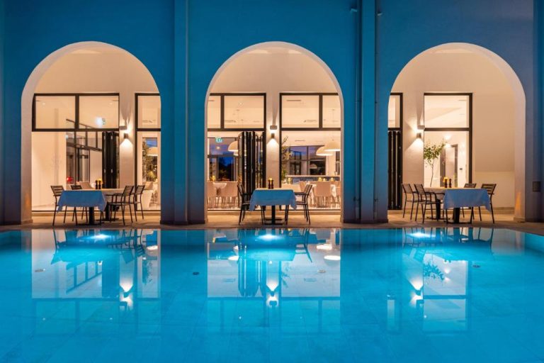 Piscina interior iluminada del Miramare Hotel con terraza de restaurante y arcos blancos de noche