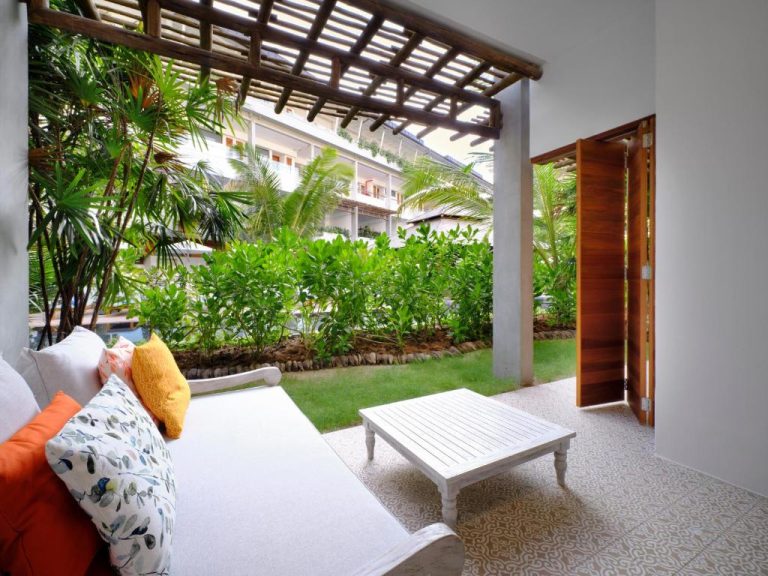 Terraza con sofá y mesa blanca rodeada de jardín tropical en Laïla Seychelles Tribute Portfolio Resort