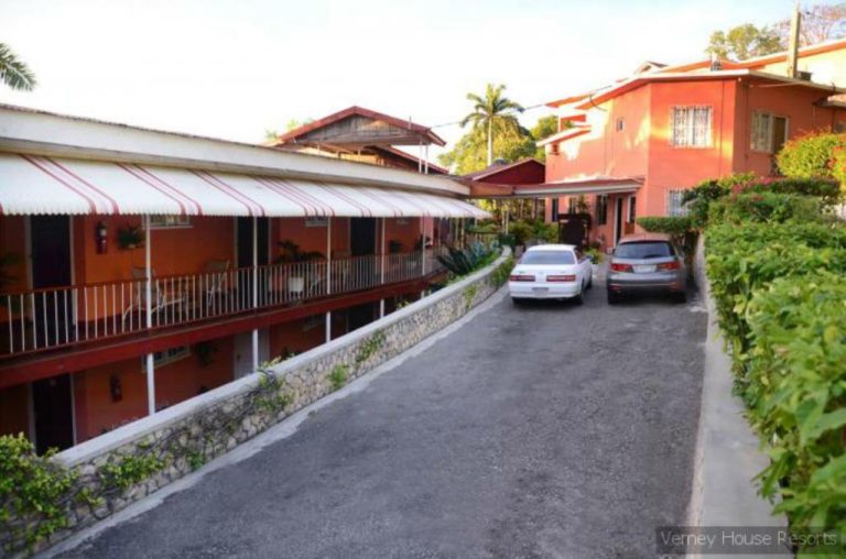 Vista del acceso y aparcamiento exterior del Verney House Resort con edificio de dos plantas y jardines