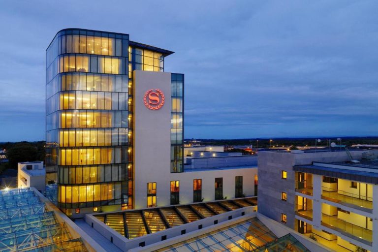Vista aérea nocturna de la fachada exterior del Sheraton Athlone Hotel con torre de cristal iluminada