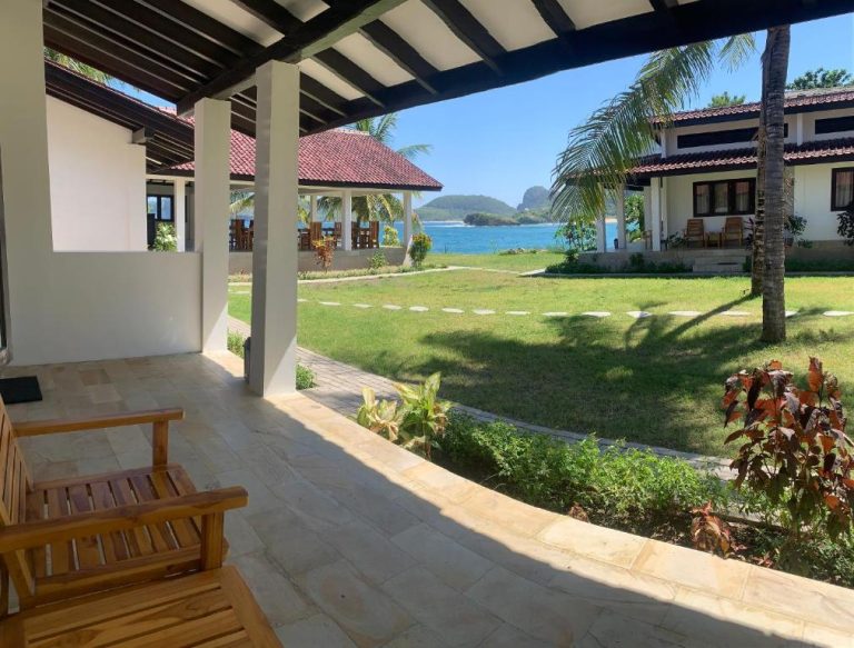 Terraza con sillas de madera y vistas al mar en Balong Balong Surf Bungalows & Restaurant