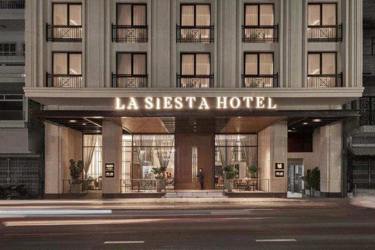 Fachada exterior nocturna del La Siesta Premium Saigon con entrada iluminada y arquitectura elegante