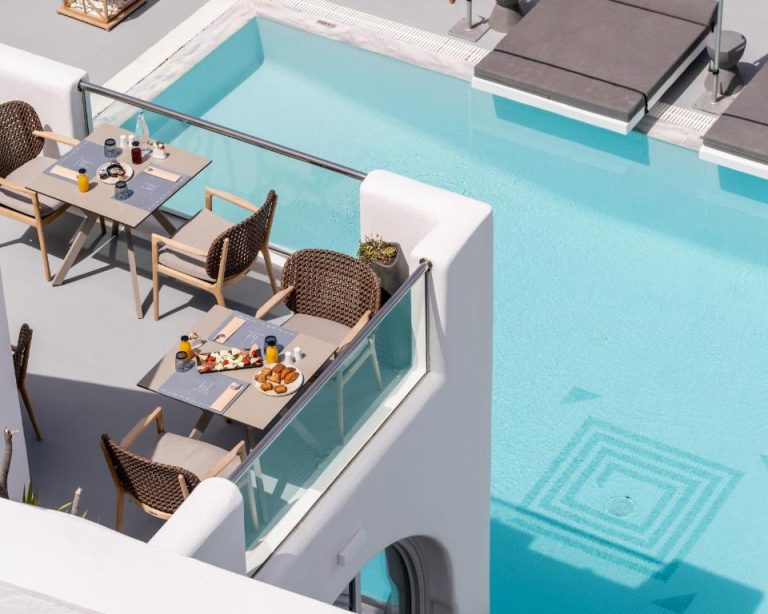 Terraza con mesas de desayuno junto a la piscina exterior del Belvedere Suites en Santorini