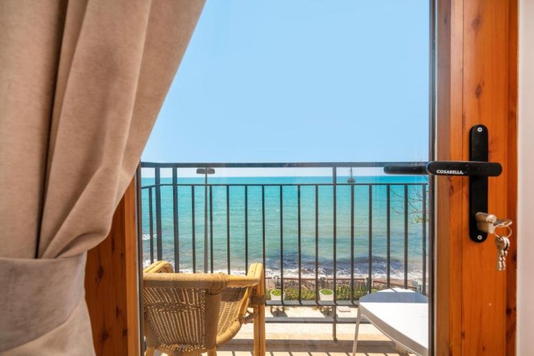 Balcón con sillas de mimbre y vistas al mar turquesa en Beach House Hotel