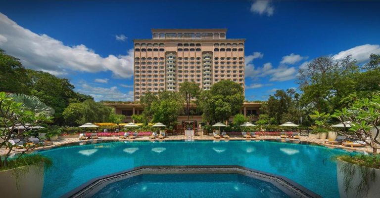 Piscina exterior con jardines tropicales y tumbonas del Taj Mahal Hotel en Nueva Delhi
