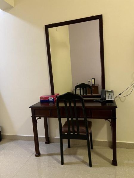 Escritorio de madera con silla y espejo de cuerpo entero en habitación del Ibra Plaza Hotel