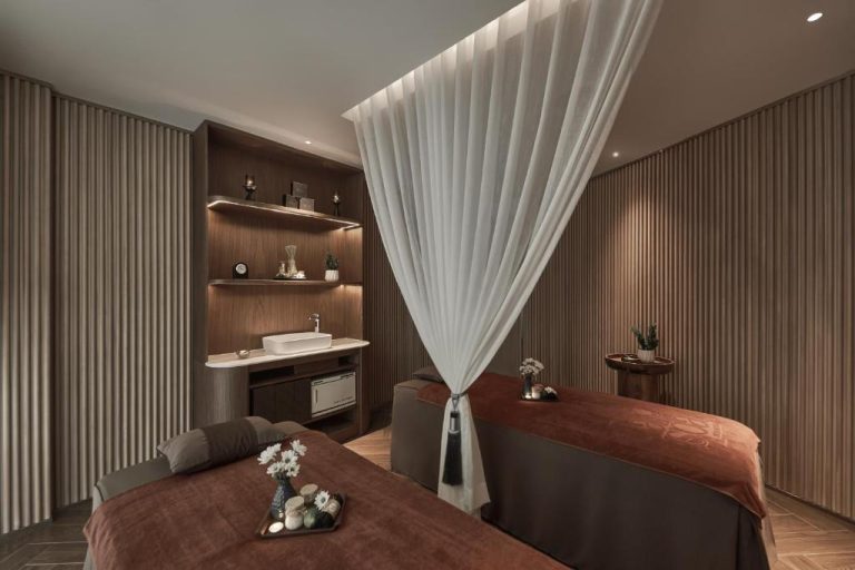 Sala de tratamientos spa con dos camillas y cortinas blancas en La Siesta Premium Saigon