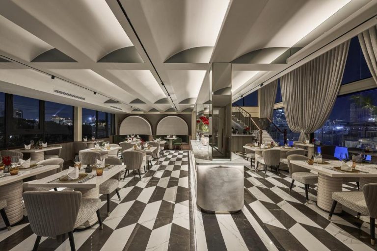 Elegante restaurante del La Siesta Premium Saigon con suelo de ajedrez y vistas nocturnas a la ciudad