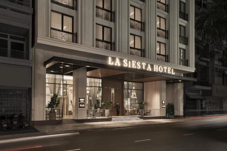 Fachada exterior nocturna del La Siesta Premium Saigon Hotel con entrada iluminada y arquitectura clásica