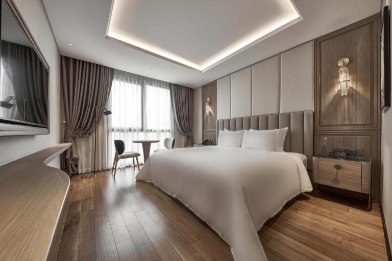 Habitación deluxe con cama king size y suelo de madera en La Siesta Premium Saigon