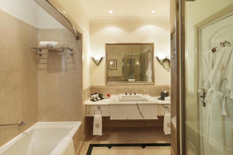Baño de lujo con bañera y lavabo de mármol en The Imperial New Delhi, con albornoz y amenities