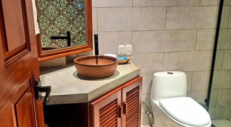 Baño rústico con lavabo artesanal de cerámica y sanitario moderno en Hotel El Guayacán
