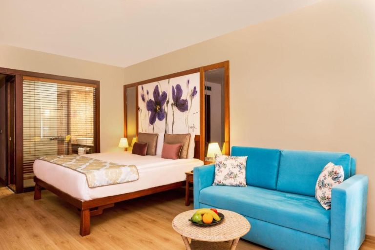 Habitación suite con cama doble y sofá azul en Asteria Family Resort Belek, Turquía
