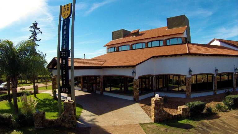 Fachada exterior del hotel Termas Posada del Siglo XIX con techo de tejas y jardines