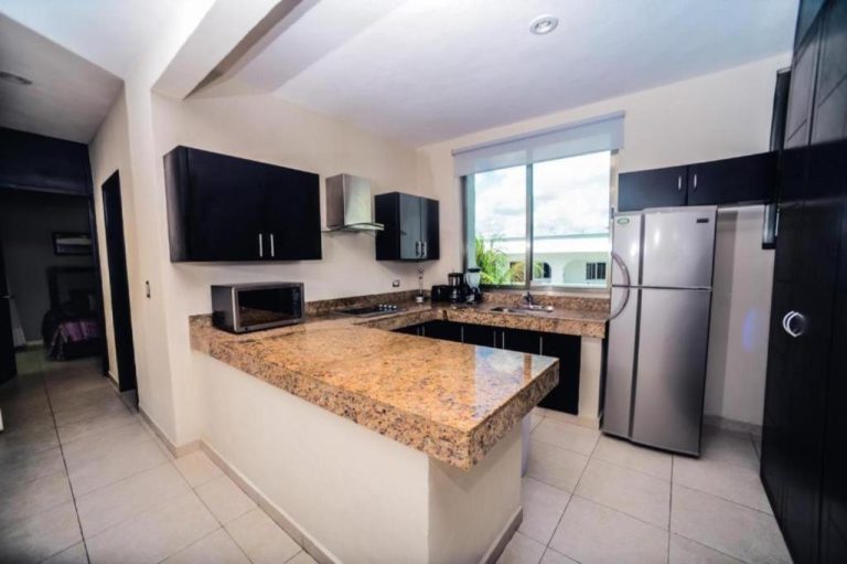 Cocina totalmente equipada con encimera de granito y refrigerador en el hotel Encanto Riviera