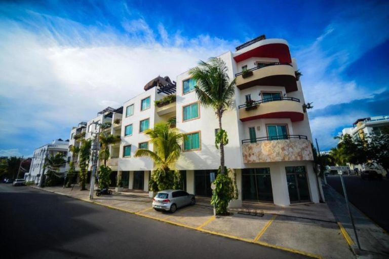 Fachada exterior del hotel Encanto Riviera con palmeras y balcones en Playa del Carmen