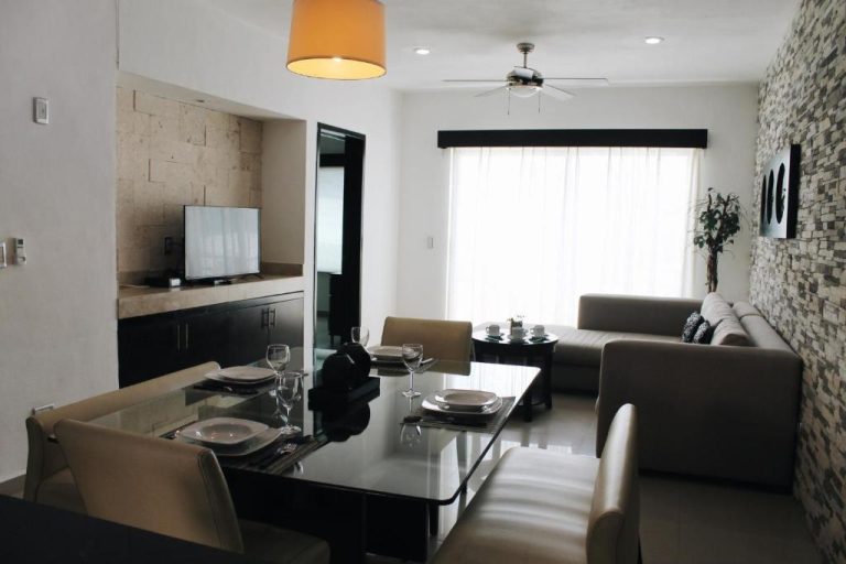 Sala de estar y comedor moderno con sofás y mesa de cristal en apartamento del Encanto Riviera