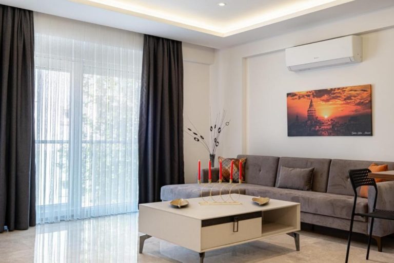 Salón moderno con sofá gris y mesa de centro en el Belek Deluxe Suit con vistas al balcón