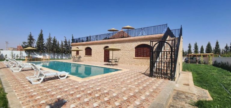 Piscina exterior con tumbonas y terraza superior en Auberge Dar Laazouzi, rodeada de jardín