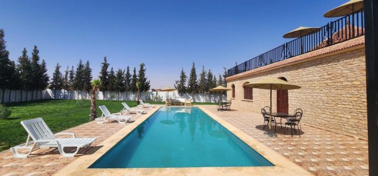Piscina exterior con tumbonas y sombrillas en Auberge Dar Laazouzi rodeada de jardín y terraza