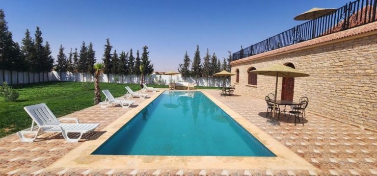 Piscina exterior con tumbonas y jardín verde en Auberge Dar Laazouzi con terraza y sombrillas