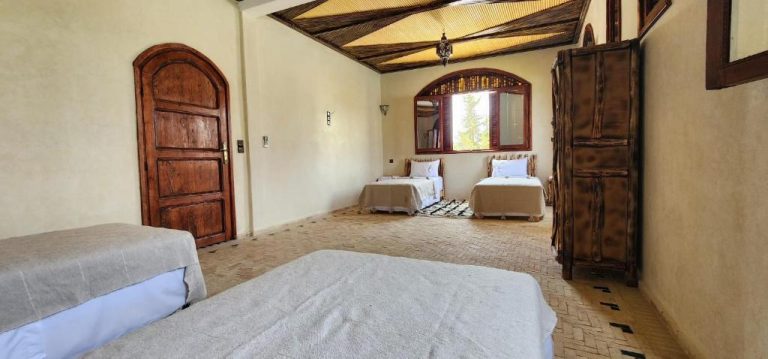 Habitación triple con decoración rústica marroquí y puertas de madera en Auberge Dar Laazouzi