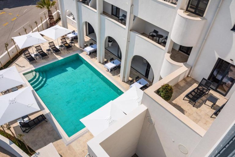 Vista aérea de la piscina exterior y terraza con tumbonas del Miramare Hotel de arquitectura mediterránea
