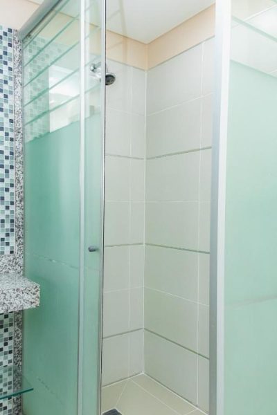 Cabina de ducha con mampara de cristal y azulejos blancos en el Awa Resort Hotel