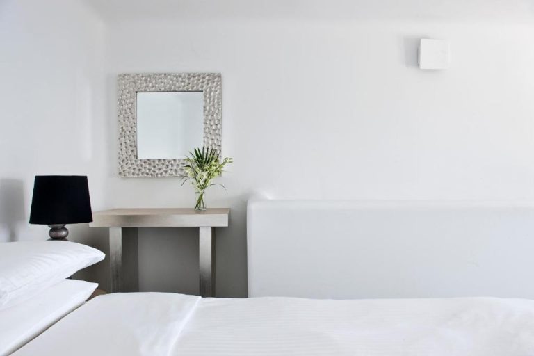 Habitación doble minimalista en blanco con espejo plateado y flores en Belvedere Suites
