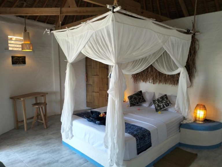 Habitación con cama de dosel y mosquitera blanca en Shaya Cottage, decoración tropical balinesa