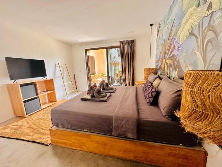 Suite con cama king size y decoración tropical en Zibá Home Suites, con mural de selva y terraza