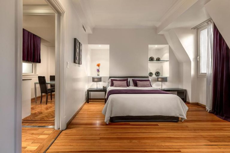 Suite con cama doble, suelo de parquet y sala de estar en Broadway Hotel & Suites