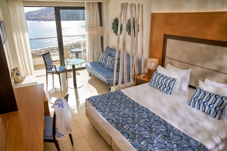 Habitación doble con cama king, decoración azul y blanca y vistas al mar en Lindos Bay Hotel