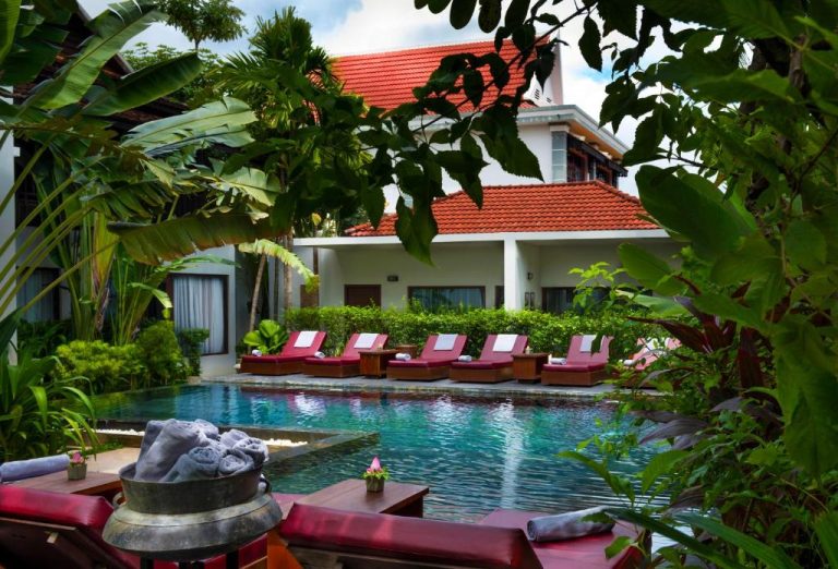 Piscina exterior rodeada de vegetación tropical con tumbonas en Sokkhak Boutique Resort & Spa