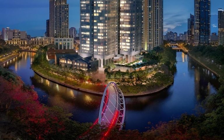 Vista aérea nocturna del Fraser Residence River Promenade Singapur con río y puente iluminado