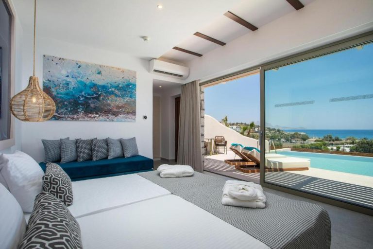 Habitación de lujo con cama doble, sofá azul y vistas a la piscina privada y el mar en Lindos Bay Hotel