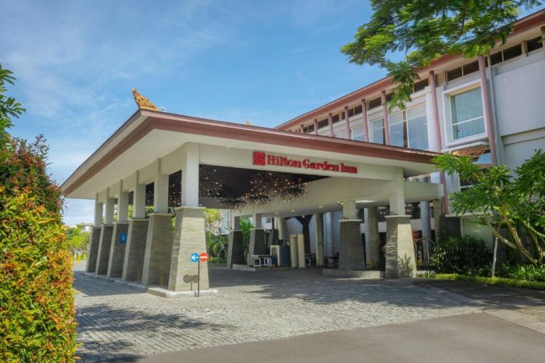 Entrada principal del Hilton Garden Inn Bali Ngurah Rai Airport con porche cubierto y jardines tropicales