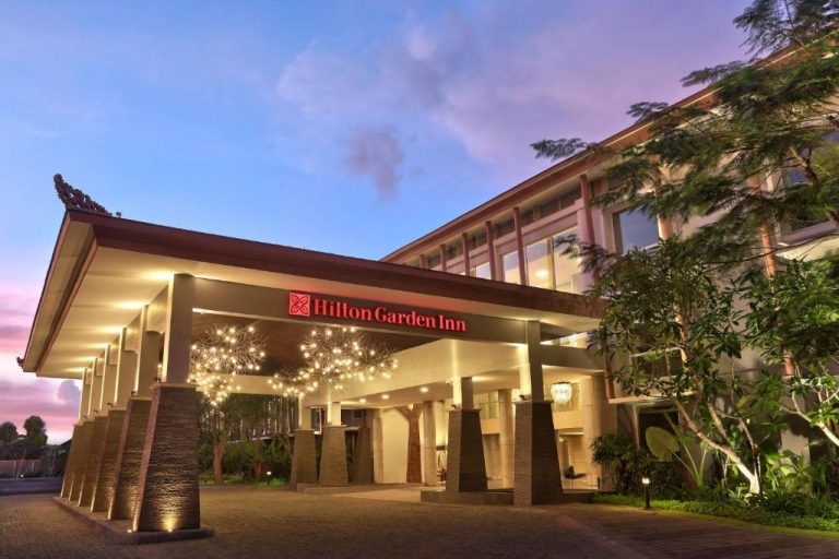 Entrada principal iluminada del Hilton Garden Inn Bali Ngurah Rai Airport al atardecer
