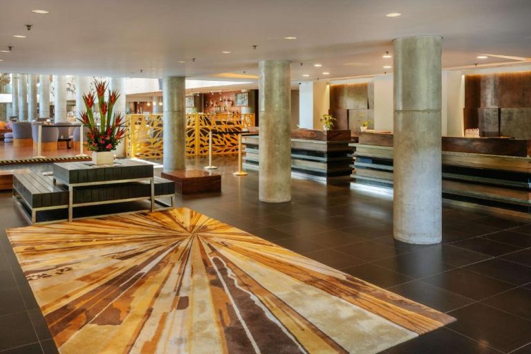 Amplio lobby con recepción y alfombra decorativa del Hilton Garden Inn Bali Ngurah Rai Airport