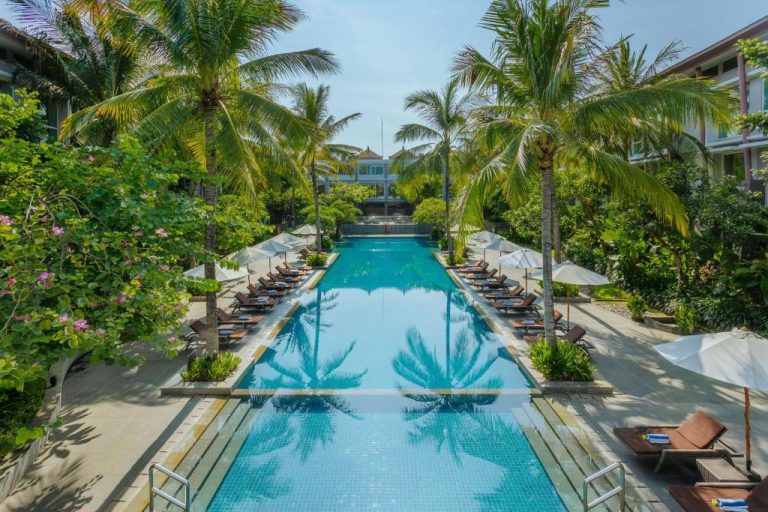 Piscina exterior con tumbonas y palmeras tropicales del Hilton Garden Inn Bali Ngurah Rai Airport