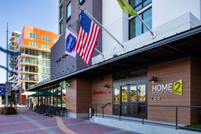 Fachada exterior del Home2 Suites by Hilton Tampa Downtown con Hampton Inn y Starbucks en primer plano